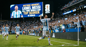 Lionel Messi celebrates scoring his 18th historic World Cup goal in front of a stadium screen reading All-Time World Cup Top Scorer.
